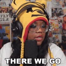 a woman wearing headphones and a winnie the pooh hat says " there we go "