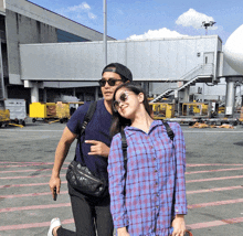 a man and a woman are posing for a picture in front of an airport