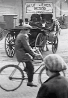 a black and white photo of a man riding a bike