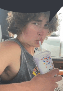 a man drinking a milkshake with sprinkles from a cup with a straw