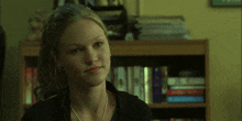 a woman sitting in front of a bookshelf with books on it and a sign that says ' freedom ' on it