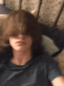 a person with long hair is laying on a bed with their hair covering their eyes .