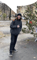 a young man standing next to a christmas tree giving the thumbs up sign