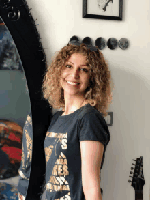 a woman with curly hair wearing a black shirt that says ' s ' on it