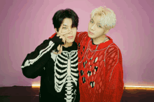 a man in a skeleton sweater and a man in a red sweater pose for a picture