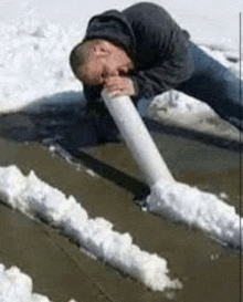 a man is laying on the ground smoking a cocaine pipe made out of snow .