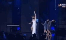 a woman in a white dress is singing into a microphone on stage