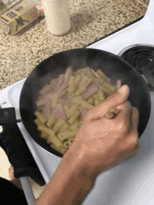 a person is cooking macaroni and cheese in a pan on a stove .