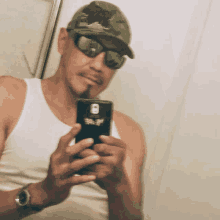 a man wearing sunglasses and a hat is taking a picture of himself in a mirror