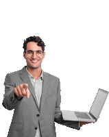 a man in a suit holding a laptop and pointing at the camera