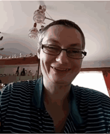 a woman wearing glasses and a striped shirt is smiling for the camera .