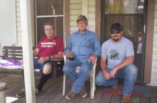 three men sitting on a porch one wearing a arkansas football shirt