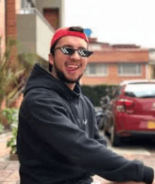 a man wearing sunglasses and a red hat is sitting on a bench .