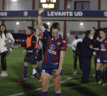 a woman in a levante ud jersey holds her hand up