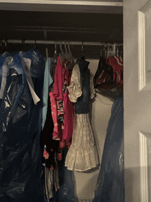 a closet filled with clothes including a white dress and a pink jacket