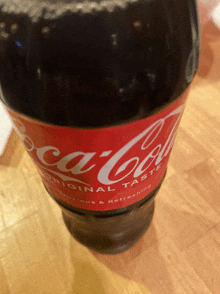 a close up of a bottle of coca cola on a wooden table