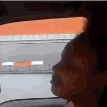 a woman is sitting in a car looking out the window at a truck .