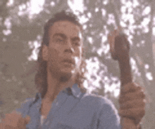 a man in a blue shirt is holding a stick in his right hand .