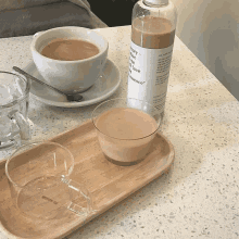 a bottle with the word essence on it sits on a wooden tray next to a cup of coffee