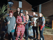 a man in a plaid suit is holding a guitar while standing with a group of people