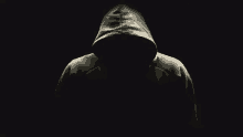 a person wearing a hooded sweatshirt is standing in the dark