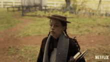 a girl in a hat and scarf is holding a book in front of a sign that says netflix on it