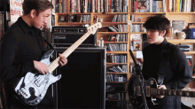 a man playing a guitar next to a boy playing a guitar in front of a sign that says no parking