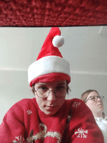 a person wearing glasses and a santa hat looks at the camera