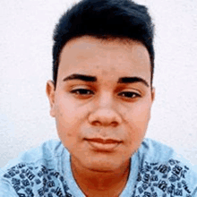 a close up of a man 's face wearing a blue shirt and looking at the camera .