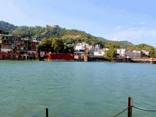 a large body of water with buildings on the shore and mountains in the background