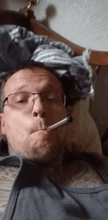 a man wearing glasses is smoking a cigarette in bed