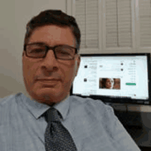 a man in a suit and tie is sitting in front of a computer .