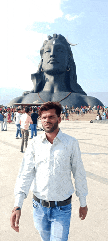 a man stands in front of a large statue of a woman