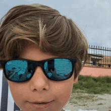 a young boy wearing ray-ban sunglasses takes a picture