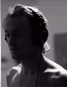 a man without a shirt is wearing headphones while listening to music