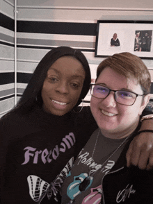 a woman wearing a freedom shirt is standing next to another woman wearing a rolling stones shirt