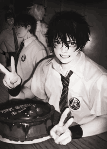 a black and white photo of a boy giving a peace sign in front of a cake that says happy birthday