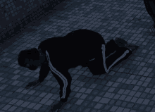 a person wearing a black adidas tracksuit is kneeling on the ground