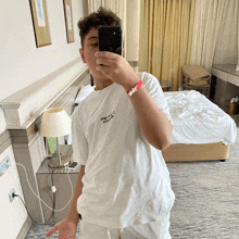 a young boy taking a picture of himself in a hotel room wearing a white shirt that says " baby i love you "