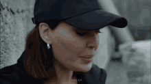 a close up of a woman wearing a baseball cap and earrings