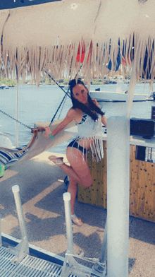 a woman in a bikini is standing in a hammock on a boat