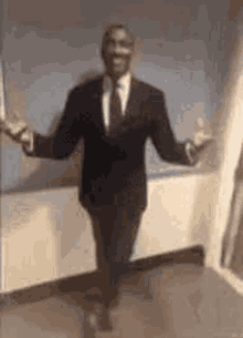 a man in a suit is dancing in a room with his arms outstretched .