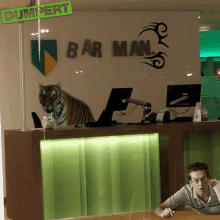 a tiger is sitting at a desk in front of a sign that says bar man