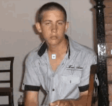 a young man is sitting in a chair with his eyes closed and his shirt has the letter w on it .