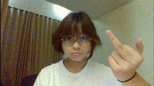 a girl wearing glasses and a white shirt giving the middle finger