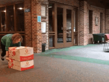 a woman in a green shirt is pushing a stack of boxes that say ' strawberry shortcake ' on the front