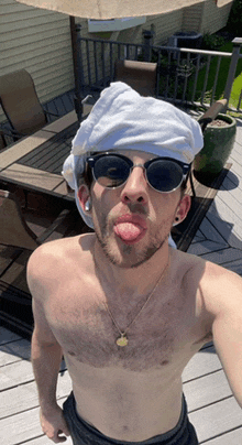 a shirtless man wearing sunglasses and a towel on his head is sticking out his tongue