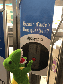 a stuffed dinosaur is standing next to a sign that says besoin d' aide une question appuyez ici