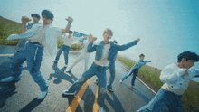 a group of young men are dancing on a road with a sign in the background that says ' open '