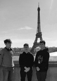 three young men are posing in front of the eiffel tower